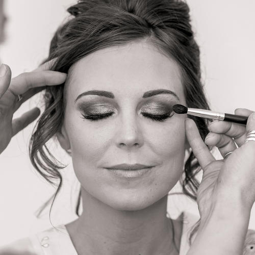 Black and white image of a bride having her makeup applied by Rhiannon Pritchard.